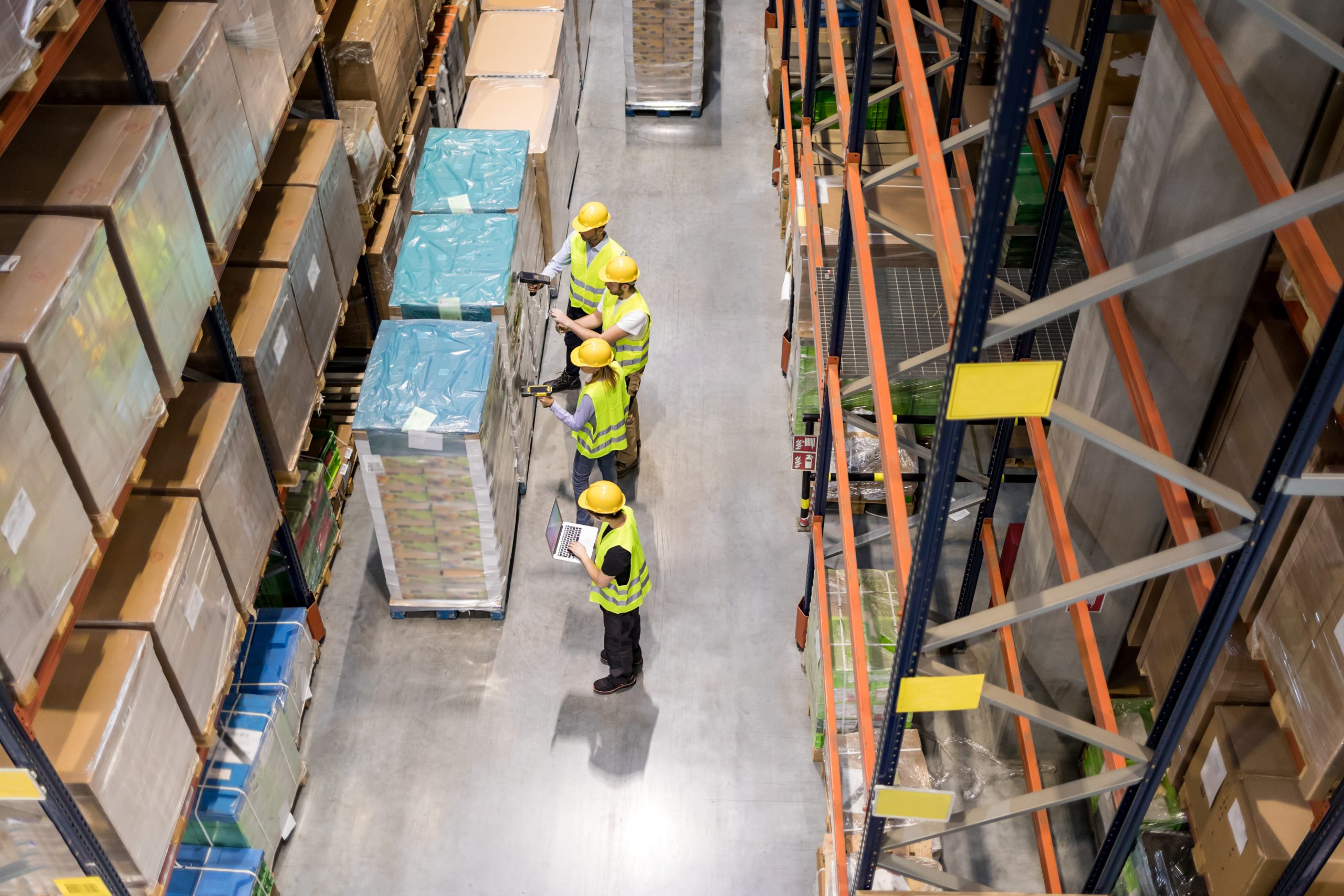 Group of warehouse workers scanning packages on pallets, view from above