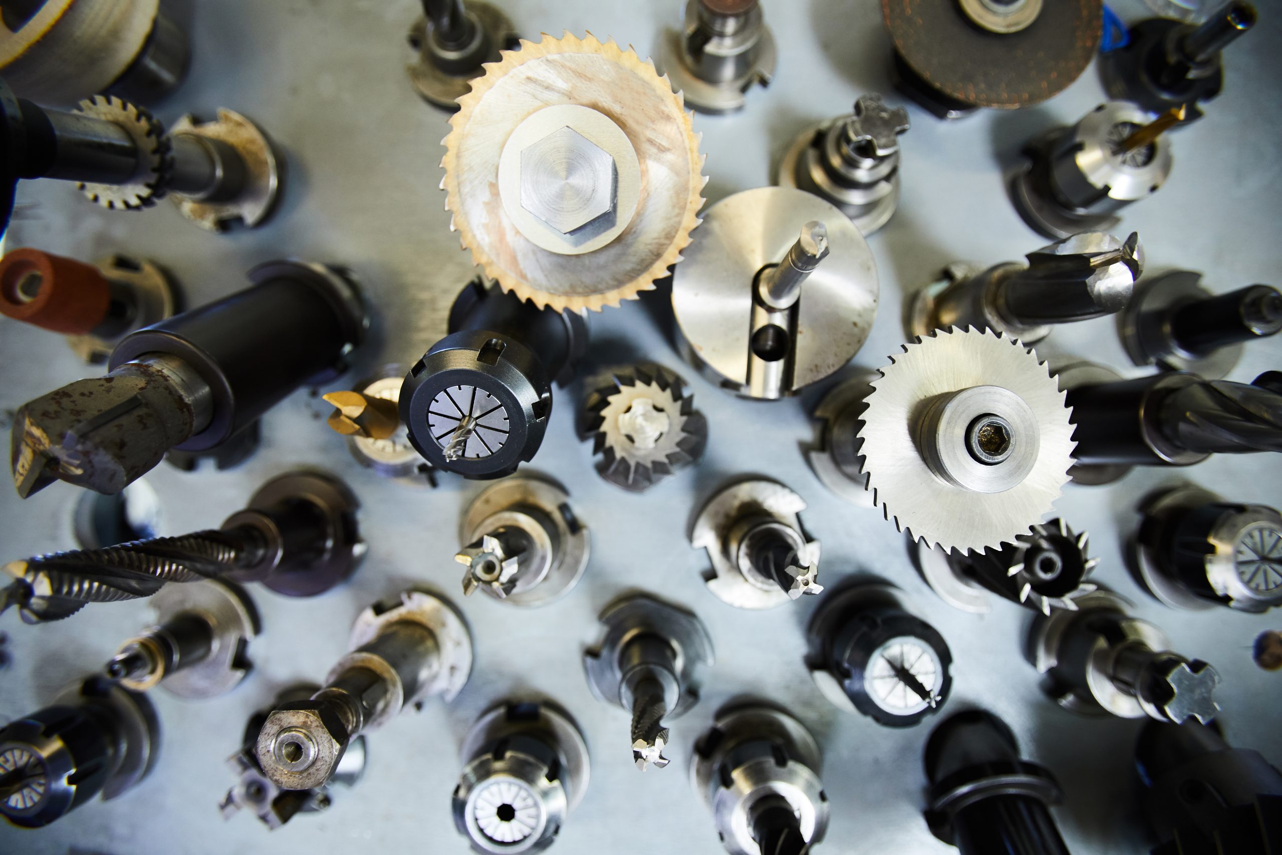 High angle view of metal milling cutters with various bits on steel table