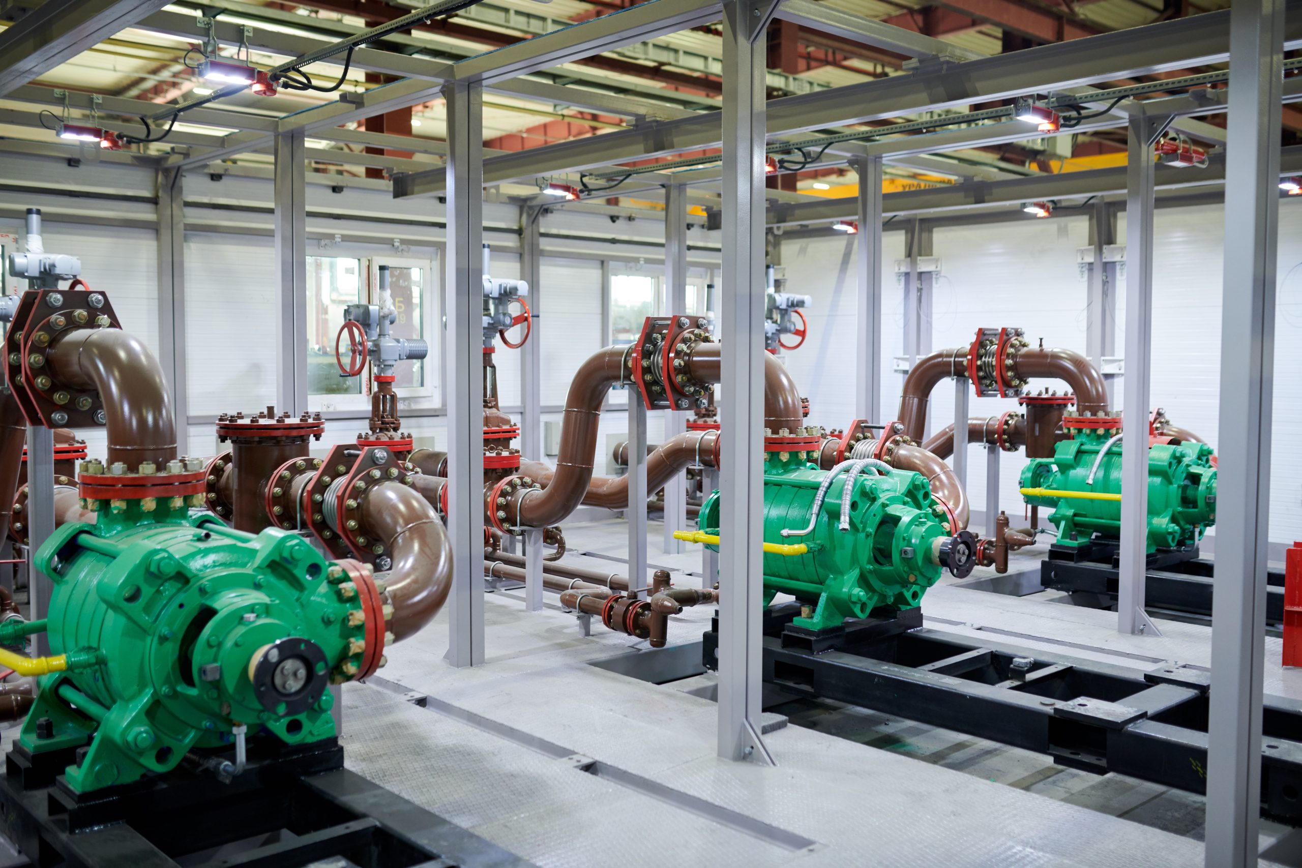 Green industrial pumps and connected piping inside a facility