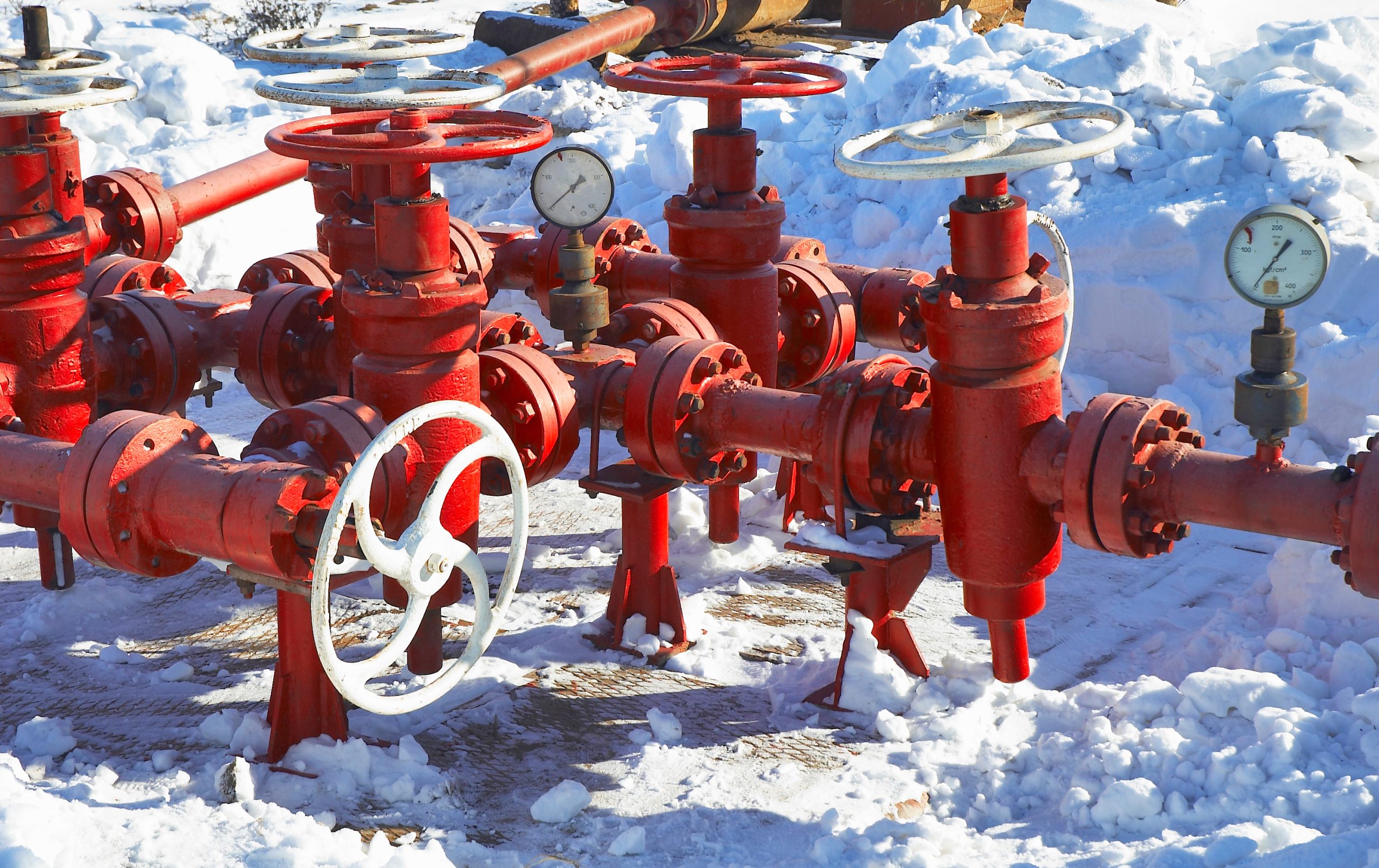 Red pipeline valves and pressure gauges in snow