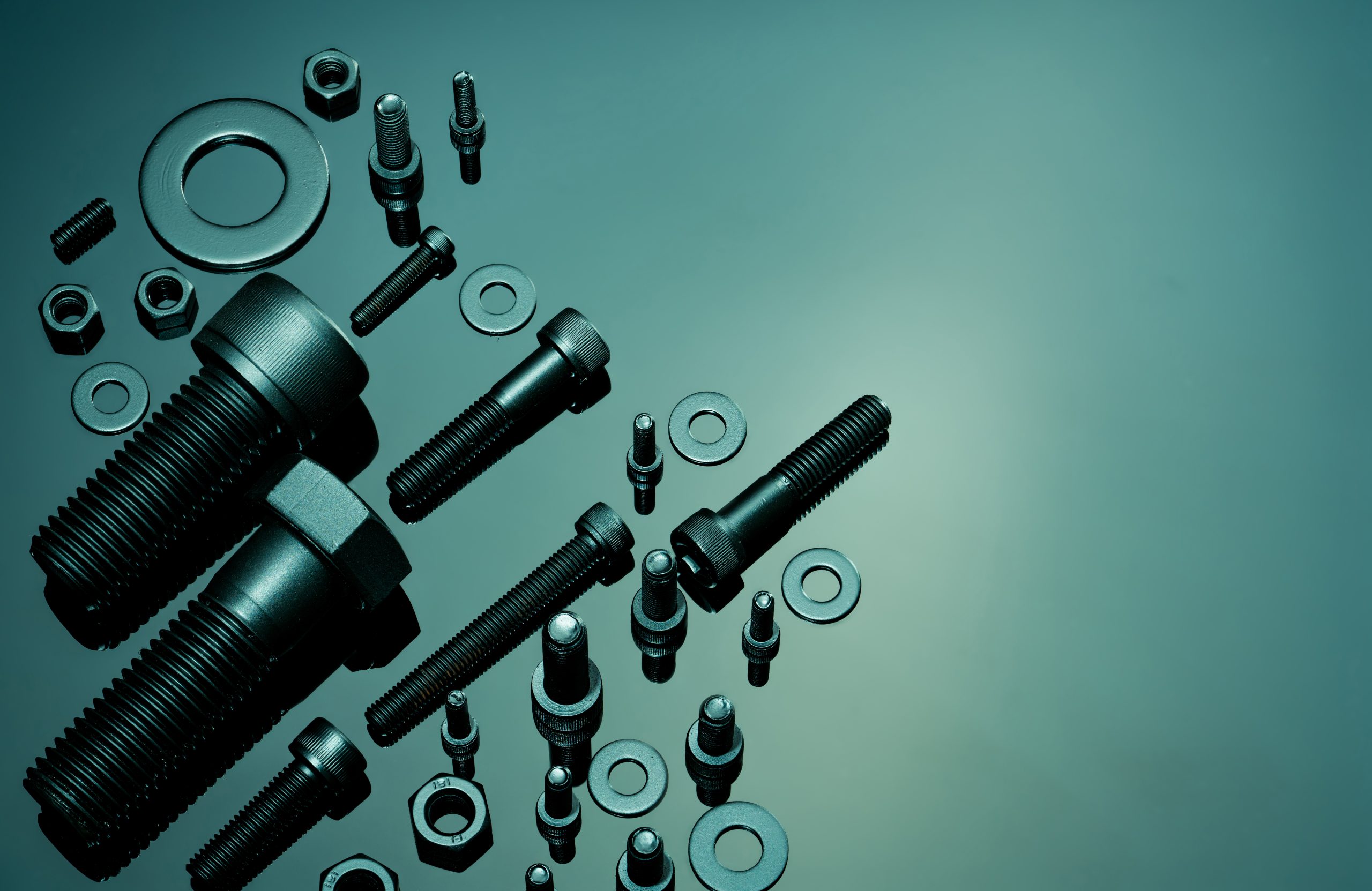 Metal bolts nuts and washers on a teal surface